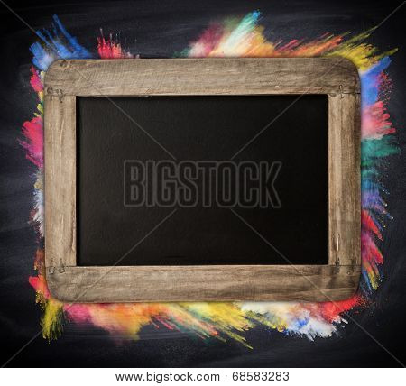 Wooden blackboard with free space for text, colored freeze motion of powder