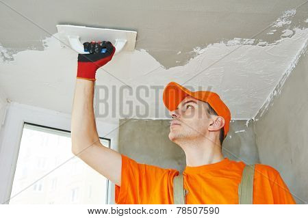Plasterer at indoor ceiling renovation decoration with float and plaster