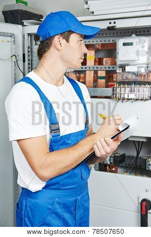 Young adult electrician builder engineer inspecting electric counter equipment in distribution fuse box