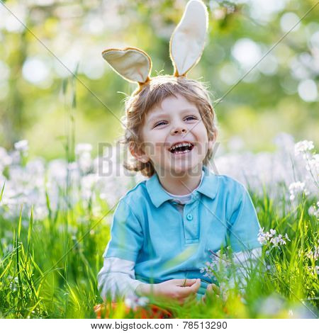 Cute Happy Little Boy Wearing Easter Bunny Ears At Spring Green Grass