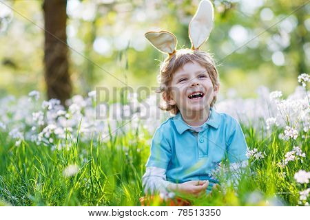 Cute Happy Little Boy Wearing Easter Bunny Ears At Spring Green Grass