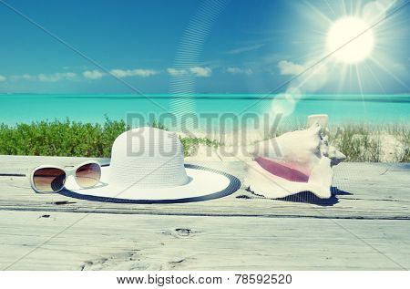 Sun glasses and hat against tropical beach of Great Exuma island, Bahamas