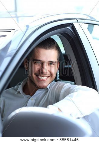 Handsome man in his new car and smiling at camera