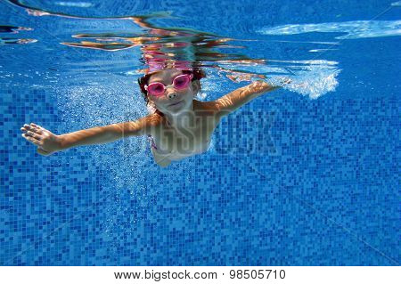 Happy girl swims in pool underwater, active kid swimming, playing and having fun