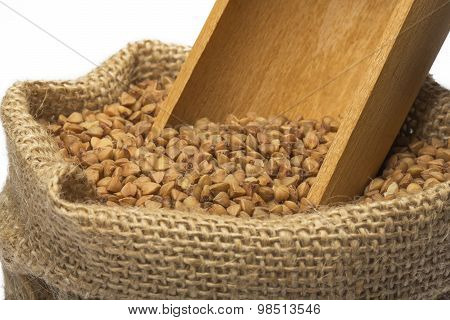 Dry buckwheat and wooden spoon in burlap bag