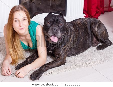woman is at home next to the fireplace with his big  Cane Corso