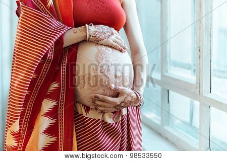 The pregnant woman belly with henna tattoo