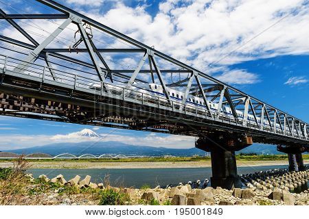 SHIZUOKA JAPAN - MAY 05 2017: Bullet train Tokaido Shinkansen running on railway bridge with view of mountain fuji.