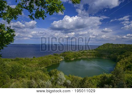 Azure Buchak lake surrounded with trees. Top view. Blue sky with clouds and blue water reservoir in background. Scenery.