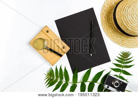 Straw hat with green leaves and old camera on white background, Summer background. Top view. Copy space. Still life. Flat lay