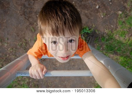 boy climbing stairs and playing outdoors on playground children activity. Child portrait from above. Active healthy childhood concept