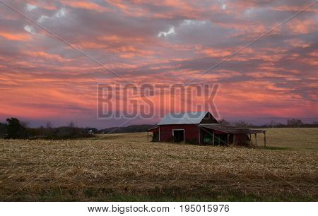 Red barn at sunset cleared field pink