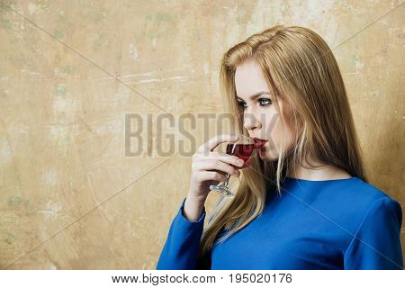 Girl In Blue Dress Drinking Red Liqueur In Glass
