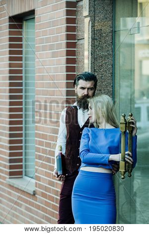 Boyfriend With Bottle Hugging Girlfriend Holding Glass Door