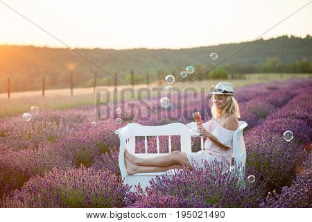 Young woman blowing soap bubbles. 20-29 years old female playing with bubble wand outdoor.