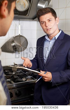 Health Inspector Meeting With Chef In Restaurant Kitchen