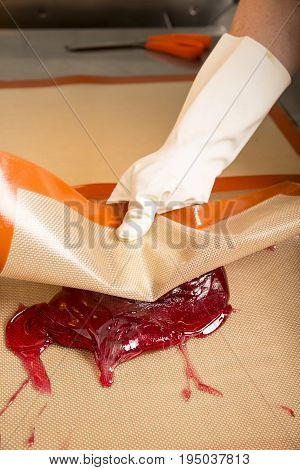 Sweets artisanal production of fruits loly pop at the factory. Close up of the hands of the employee stretching the sugar to make butterscotch fruits candies. Artisanal production in France