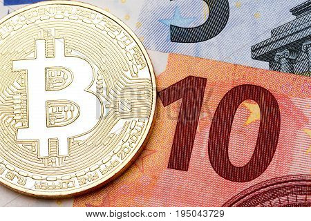 Ten euro banknote as a background for golden bitcoin. High resolution photo.