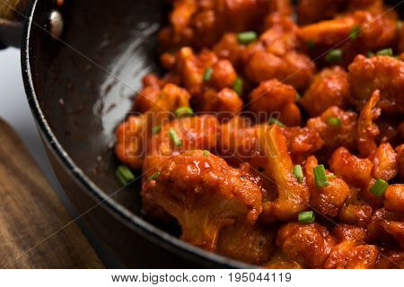 Gobi Manchurian dry - Popular street food of India made of cauliflower florets in a frying pan, selective focus