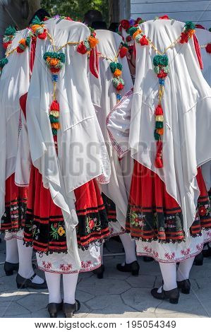 Bulgarian girls dressed in traditional folk costumes with multicolored embroidery.