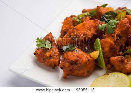 Chicken 65 - spicy deep fried Bar appetizer or quick snack from India in a bowl or plate over white background, selective focus