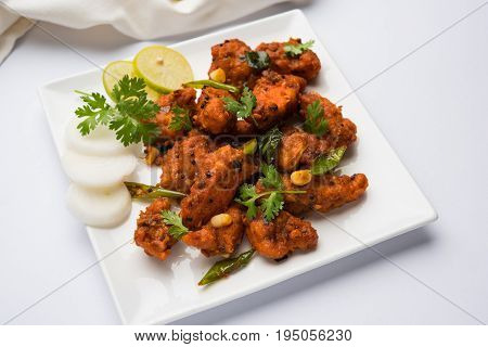 Chicken 65 - spicy deep fried Bar appetizer or quick snack from India in a bowl or plate over white background, selective focus