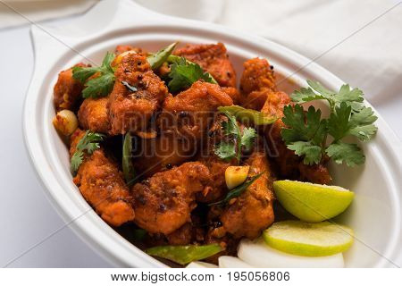 Chicken 65 - spicy deep fried Bar appetizer or quick snack from India in a bowl or plate over white background, selective focus