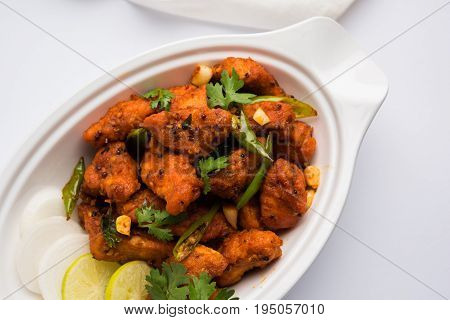 Chicken 65 - spicy deep fried Bar appetizer or quick snack from India in a bowl or plate over white background, selective focus