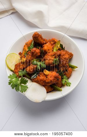 Chicken 65 - spicy deep fried Bar appetizer or quick snack from India in a bowl or plate over white background, selective focus