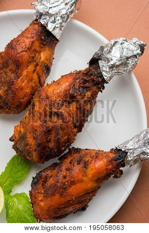 Chicken Tangri kabab or kebab - three Chicken leg pieces marinated with red sauce then grilled and served with salad. It can be served with green chutney