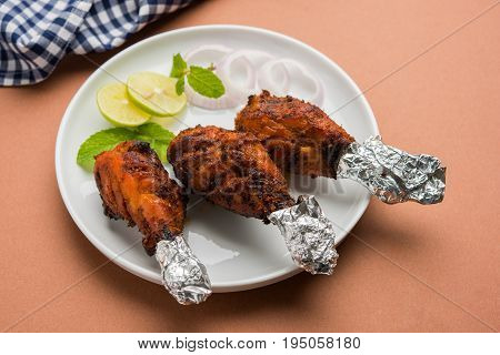 Chicken Tangri kabab or kebab - three Chicken leg pieces marinated with red sauce then grilled and served with salad. It can be served with green chutney