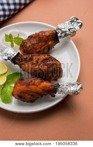 Chicken Tangri kabab or kebab - three Chicken leg pieces marinated with red sauce then grilled and served with salad. It can be served with green chutney