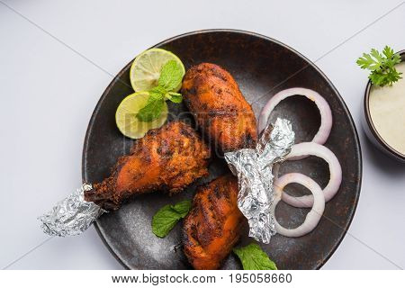 Chicken Tangri kabab or kebab - three Chicken leg pieces marinated with red sauce then grilled and served with salad. It can be served with green chutney