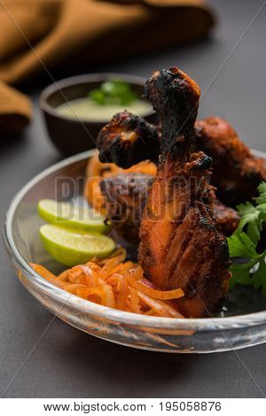 Chicken Tangri kabab or kebab - three Chicken leg pieces marinated with red sauce then grilled and served with salad. It can be served with green chutney
