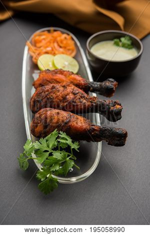 Chicken Tangri kabab or kebab - three Chicken leg pieces marinated with red sauce then grilled and served with salad. It can be served with green chutney