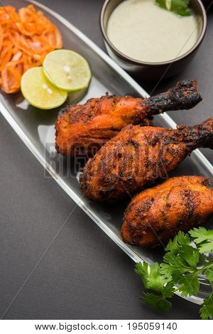 Chicken Tangri kabab or kebab - three Chicken leg pieces marinated with red sauce then grilled and served with salad. It can be served with green chutney
