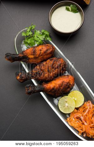 Chicken Tangri kabab or kebab - three Chicken leg pieces marinated with red sauce then grilled and served with salad. It can be served with green chutney