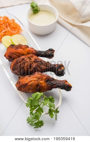 Chicken Tangri kabab or kebab - three Chicken leg pieces marinated with red sauce then grilled and served with salad. It can be served with green chutney