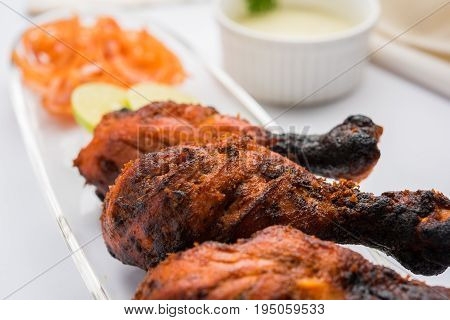 Chicken Tangri kabab or kebab - three Chicken leg pieces marinated with red sauce then grilled and served with salad. It can be served with green chutney