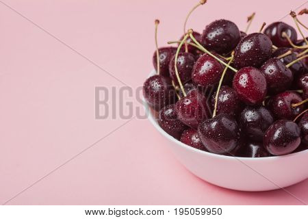 White Bowl Of Fresh Red Cherries On A Pink Background. Copy Space. Close-up