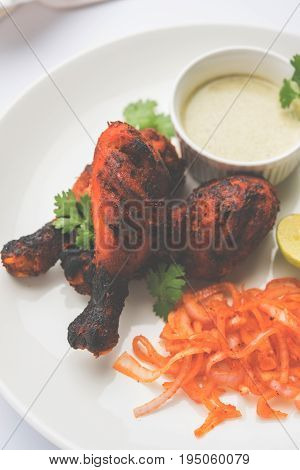 Chicken Tangri kabab or kebab - three Chicken leg pieces marinated with red sauce then grilled and served with salad. It can be served with green chutney