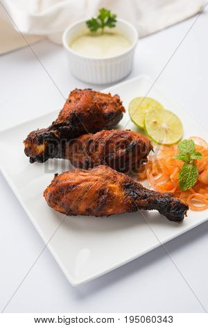 Chicken Tangri kabab or kebab - three Chicken leg pieces marinated with red sauce then grilled and served with salad. It can be served with green chutney