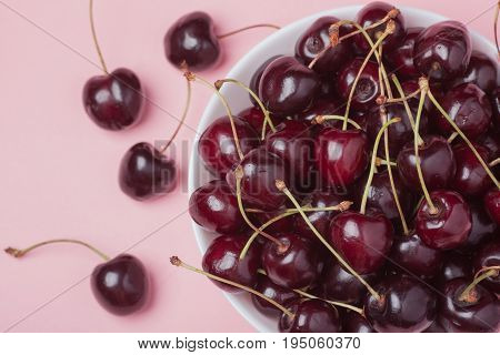 White Bowl Of Fresh Red Cherries On A Pink Background. Top View. Close-up