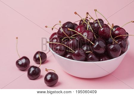 White Bowl Of Fresh Red Cherries On A Pink Background. Copy Space. Close-up