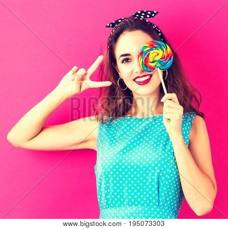 Young woman holding a lollipop on a pink background