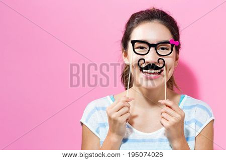 Young woman holding paper party sticks on a solid color background