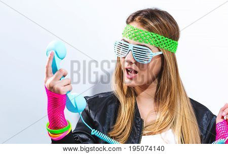 Woman in 1980's fashion with old fashioned phone on a white background