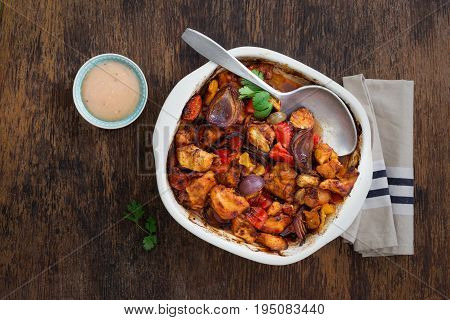 Baked chicken breast with vegetables and sauce on dark rustic wooden table with copy space top view. Dinner table concept