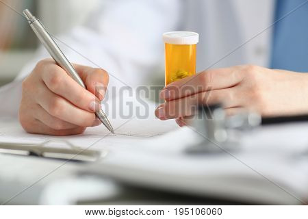 Female Doctor Hand Hold Jar Of Pills And Write Prescription