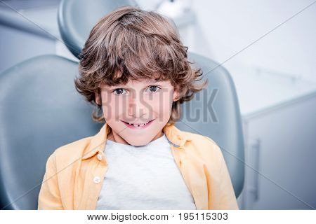 Little Smiling Boy Sitting In Chair In Dentist Office